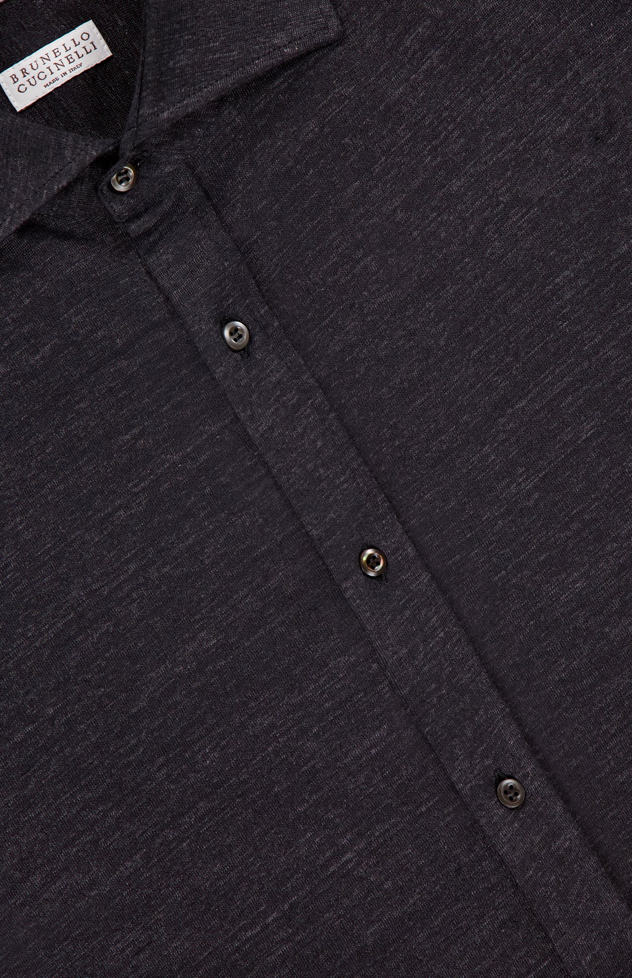 Close-up of a dark gray BRUNELLO CUCINELLI Jersey Long Sleeve Dress Shirt with a subtle textured pattern. Features three buttons and part of the collar. Made in Italy from a linen-cotton blend; the label displays the brand name.