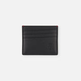 The BRUNELLO CUCINELLI Leather Cardholder with Middle Slot features black leather, three horizontal slots per side, subtle embossed branding at the bottom right, and red accents on the top corners, shown against a plain white background.
