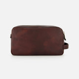 The BRUNELLO CUCINELLI Leather Dopp Kit is a rectangular, dark brown leather travel accessory—crafted in Italy—with a right-side handle and a top zipper, displayed against a plain white background; ideal for organizing your essentials in style.
