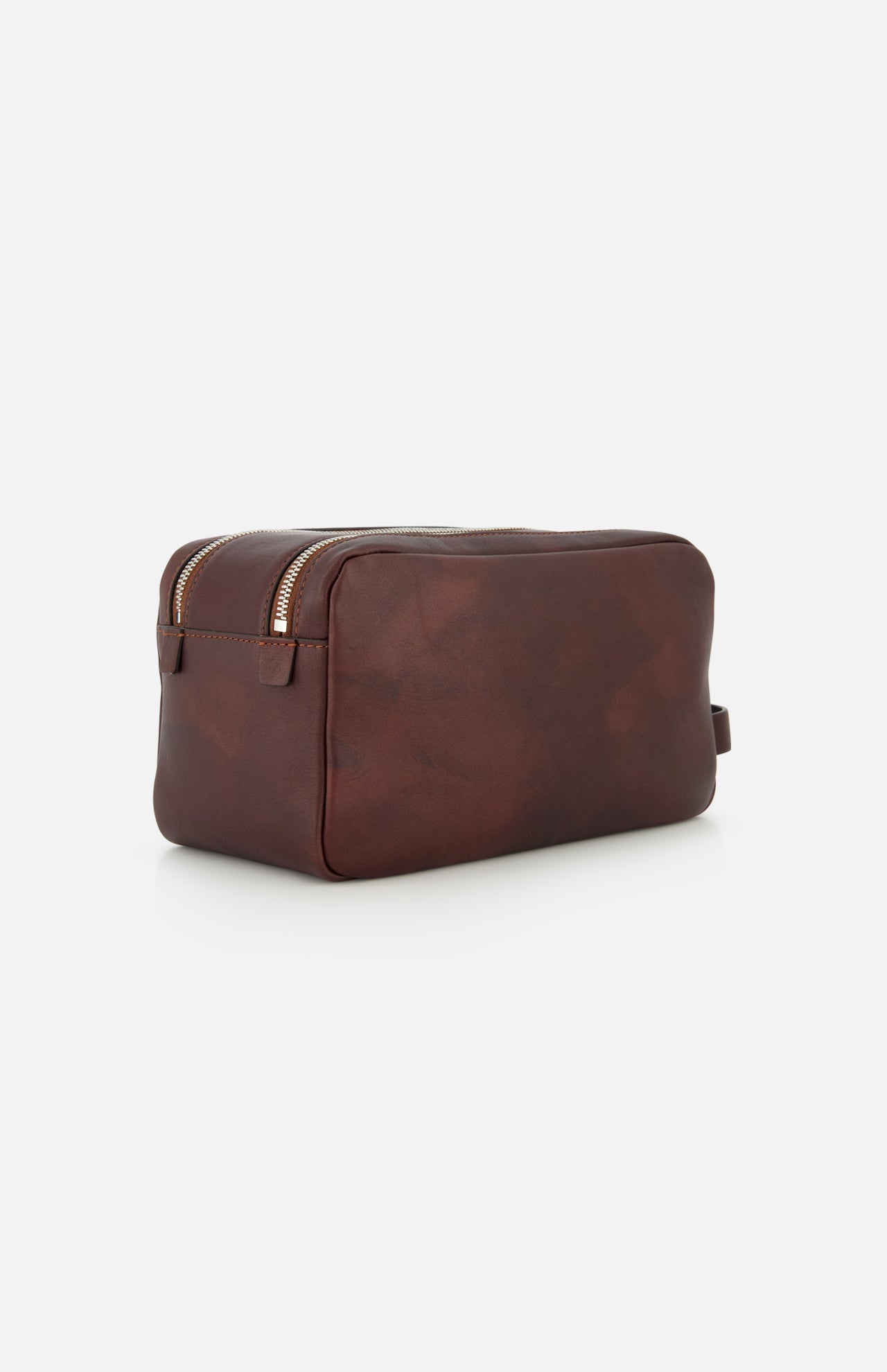 The BRUNELLO CUCINELLI Leather Dopp Kit, expertly crafted in Italy, is one of the finest travel accessories. Made from brown leather, it features a zippered top and a small handle on one end, and is displayed against a plain white background.