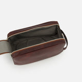 The BRUNELLO CUCINELLI Leather Dopp Kit, crafted from brown leather in Italy, is displayed open against a plain white background to showcase its spacious, lined interior and zippered closure. This elegant toiletry bag is an essential addition to your travel accessories.