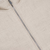 Close-up of the BRUNELLO CUCINELLI Light Full Zip Woven Jacket, made in Italy with textured cream fabric, a prominent silver zipper, and a touch of white lining visible at the collar.