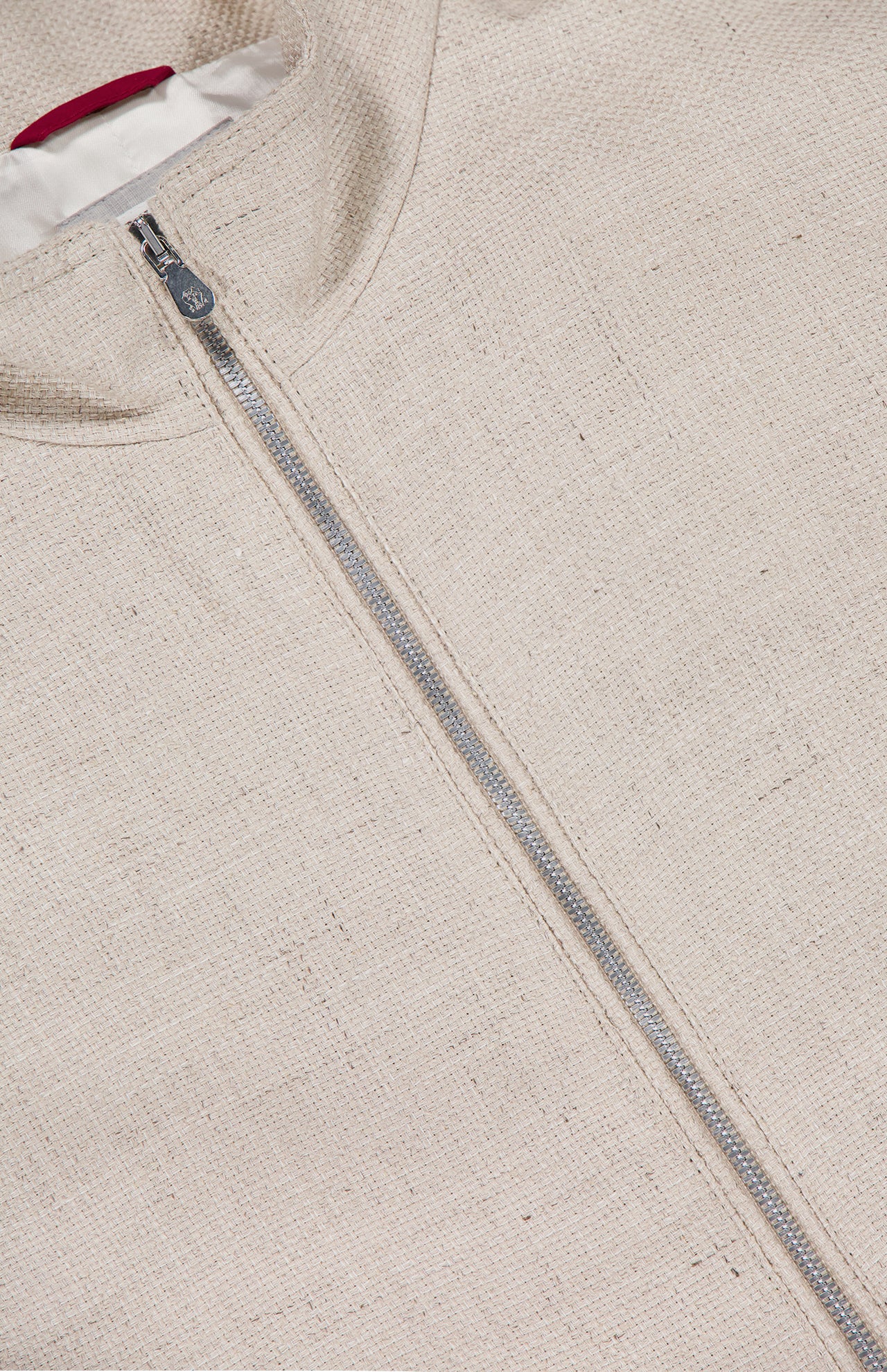 Close-up of the BRUNELLO CUCINELLI Light Full Zip Woven Jacket, made in Italy with textured cream fabric, a prominent silver zipper, and a touch of white lining visible at the collar.