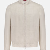 The BRUNELLO CUCINELLI Light Full Zip Woven Jacket is a cream, long-sleeve casual style with a stand collar and elastic waistband, featuring a minimalist design. Made in Italy, it is shown against a plain white background.
