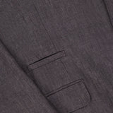 Close-up of the BRUNELLO CUCINELLI Linen Single-breasted Suit Jacket in dark brown textured fabric, highlighting the overlapping sleeve, flap pocket, and a button detail near the top right.