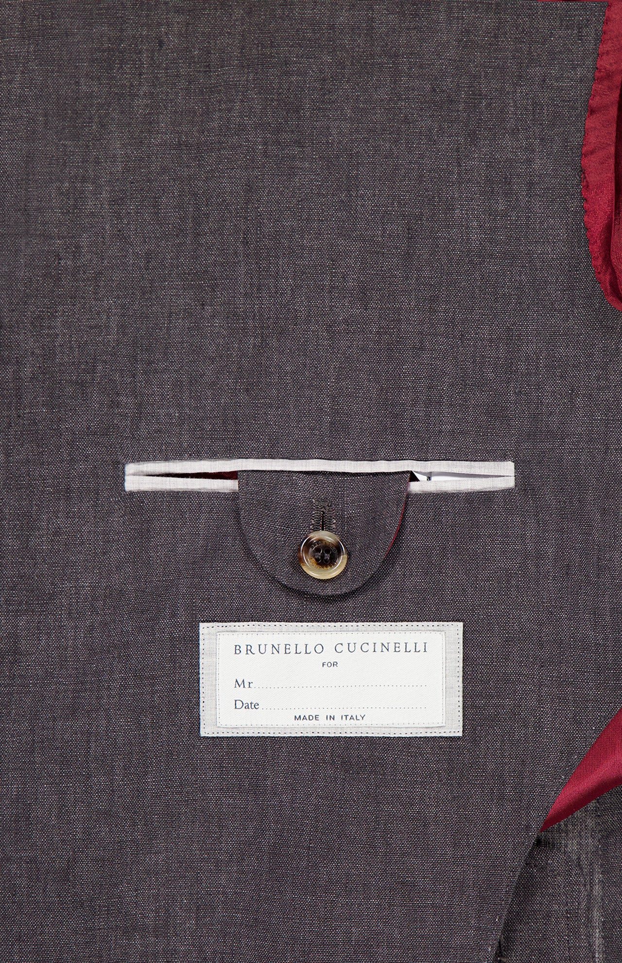 A close-up shows the inside pocket of the BRUNELLO CUCINELLI Linen Single-breasted Suit Jacket, with a button flap, red lining, and a label featuring spaces for name and date plus “Made in Italy” text.