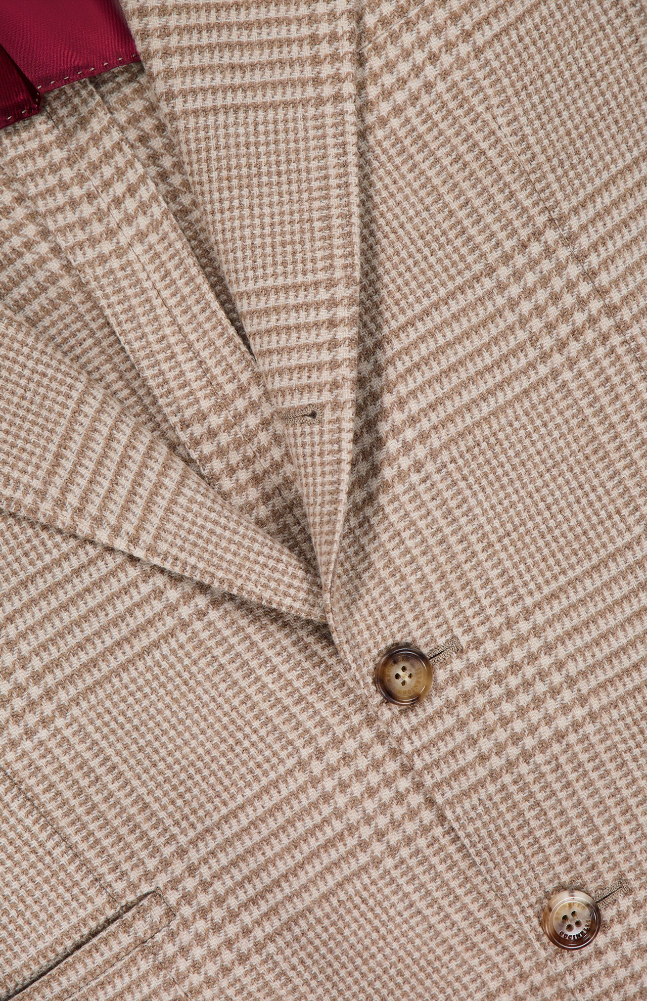 Close-up of the BRUNELLO CUCINELLI Plaid Wool-blend Sportcoat, featuring a tan houndstooth pattern with brown buttons and a glimpse of its red interior lining, highlighting the refined craftsmanship of this men's blazer.
