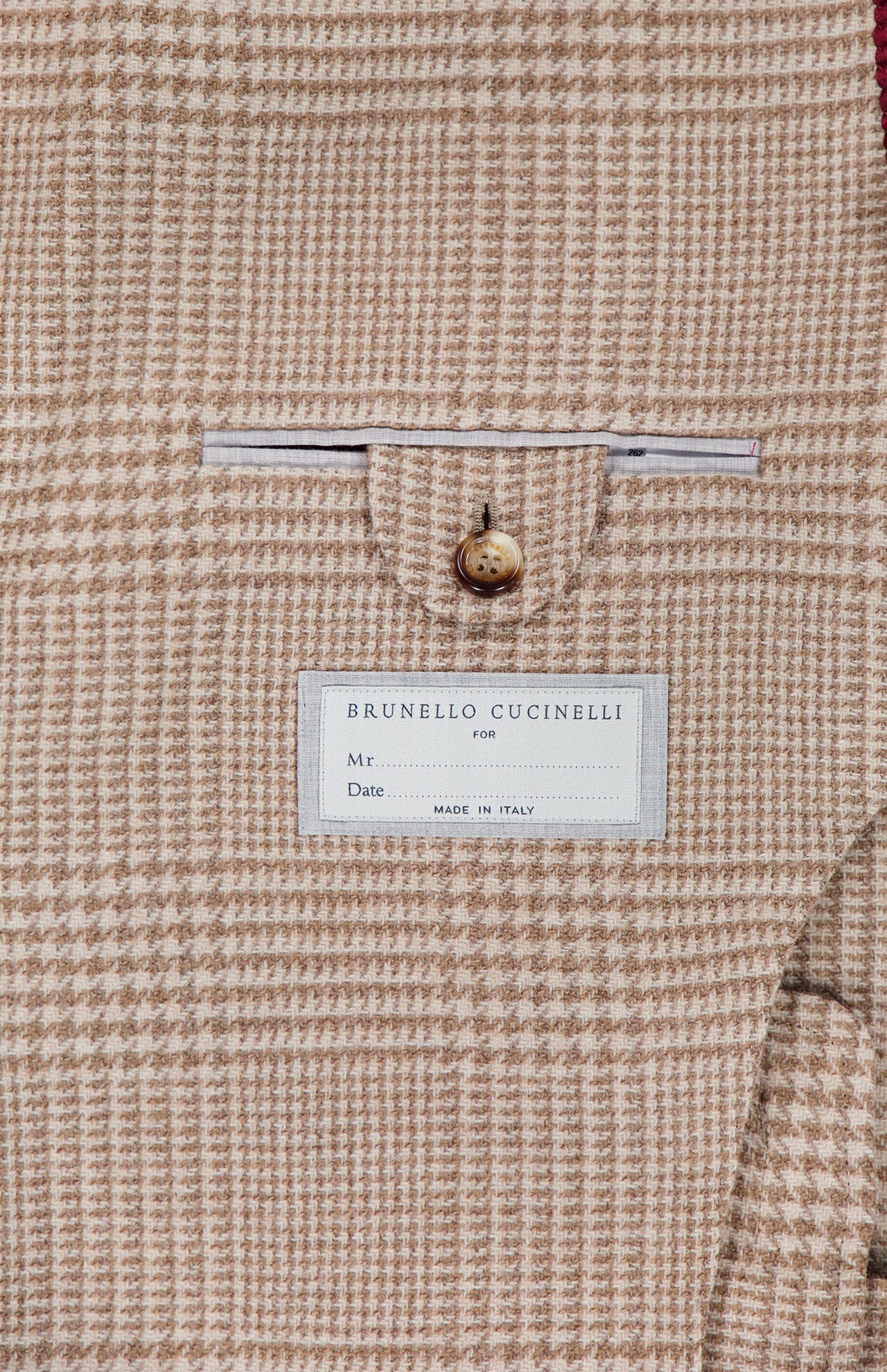 Close-up of the interior of the Plaid Wool-blend Sportcoat, featuring a white BRUNELLO CUCINELLI label and a neatly tailored small pocket above it, secured with a single tan button—an exquisite detail that highlights the exceptional craftsmanship of this luxury piece.