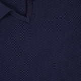 Close-up of a dark navy blue BRUNELLO CUCINELLI Polo Short Sleeve Sweater, featuring a V-neck and collar. The fine English rib knit texture and visible stitching showcase luxurious Italian craftsmanship.