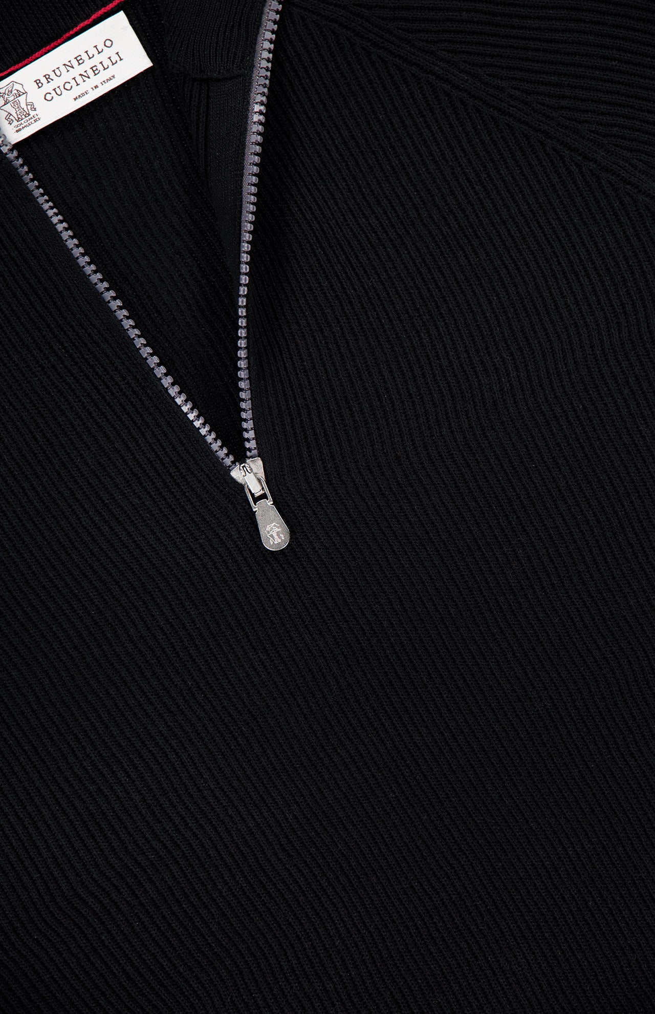 Close-up of a black BRUNELLO CUCINELLI Quarter Zip Pullover Sweater in ribbed fabric, featuring a partially open silver zipper and the brand label at the top left corner.