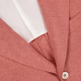 Close-up of a muted red BRUNELLO CUCINELLI sportcoat made in Italy from virgin wool, cotton, and silk. Features include a white button, white inner lining, notched lapel, and visible fabric texture.