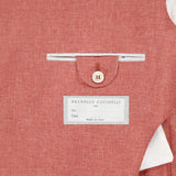 A close-up of the inside pocket of a muted red BRUNELLO CUCINELLI Virgin Wool, Cotton and Silk Sportcoat highlights a buttoned flap, white brand tag, and white lining—exquisitely crafted in Italy.
