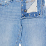 Introducing the Traditional Fit Light Denim jeans by BRUNELLO CUCINELLI: expertly crafted in Italy from premium light bluewash denim, these vintage-inspired jeans feature a partially open button fly revealing a striped inner waistband and a size 46 tag. Classic front pockets and signature visible stitching complete the timeless design.