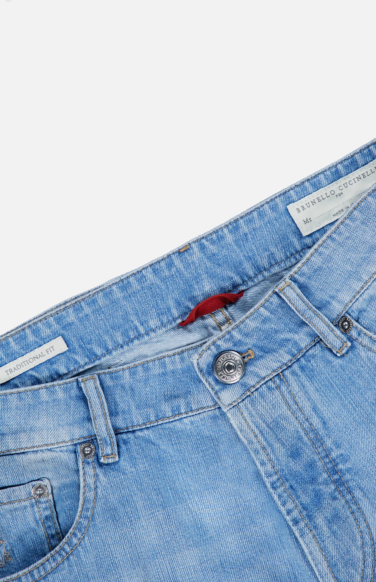 The Traditional Fit Light Denim jeans by BRUNELLO CUCINELLI are shown from the waist down at an angle, featuring a button closure, front pockets, and visible inside tags with text, including a label that reads BRUNELLO CUCINELLI. Crafted in Italy, these classic blue lightwash jeans offer timeless style.