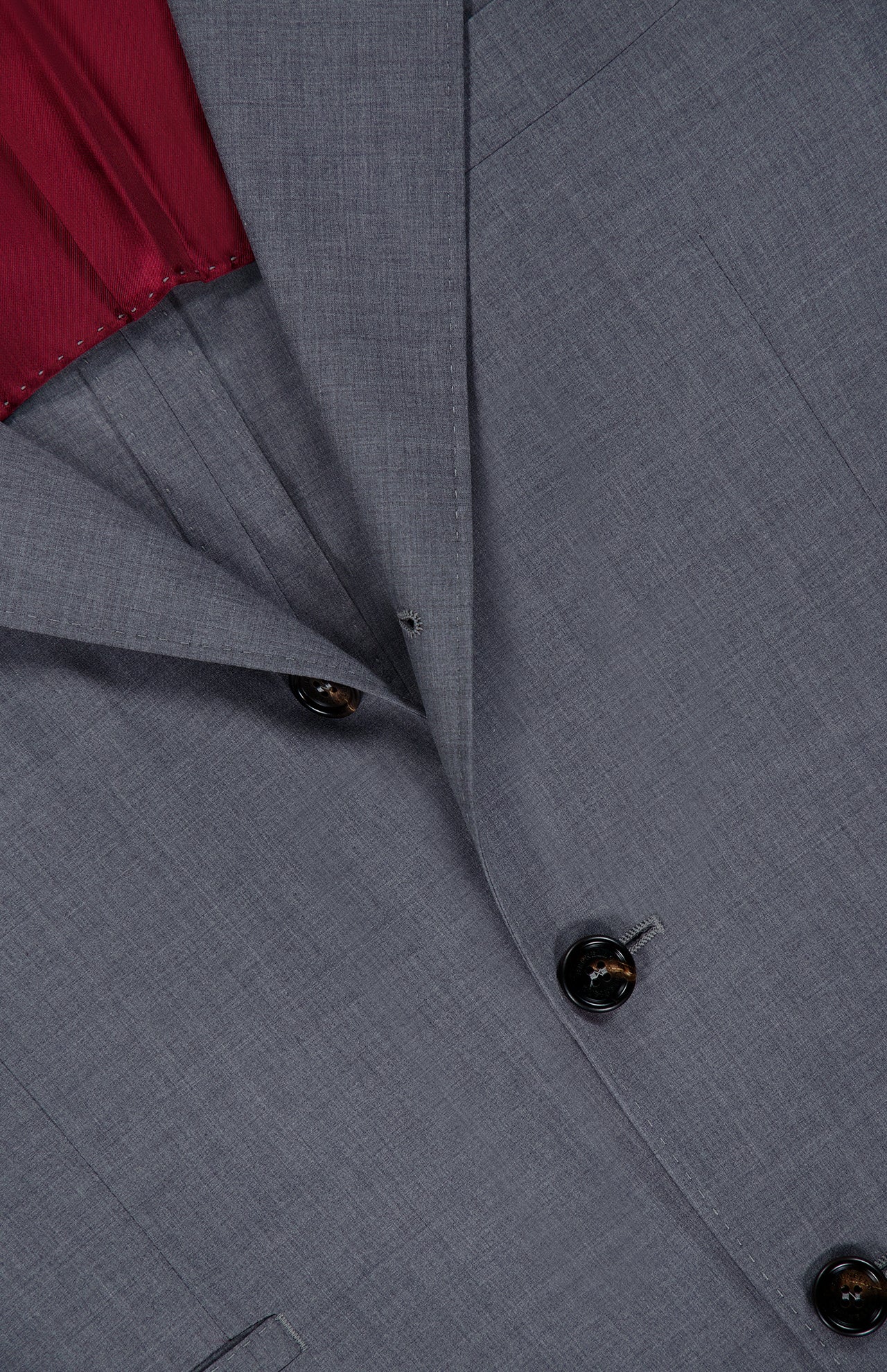 Close-up of the BRUNELLO CUCINELLI Wool and Silk Travel Blazer in grey, featuring a single-breasted design with dark buttons and a visible maroon inner lining. The refined wool and silk blend fabric offers a smooth texture, while lapel and pocket details are clearly shown—making this blazer an ideal travel jacket for any occasion.
