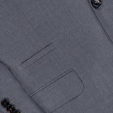 Close-up of the BRUNELLO CUCINELLI Wool and Silk Travel Blazer in grey, featuring a front pocket, a sleeve detailed with four dark buttons, and two buttons near the lapel. This single-breasted jacket seamlessly combines practicality with refined style, making it an ideal choice for any journey.