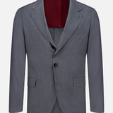 Introducing the BRUNELLO CUCINELLI Wool and Silk Travel Blazer, a versatile travel jacket in grey, expertly crafted from a luxurious blend of wool and silk. This single-breasted blazer features two buttons, notched lapels, flap pockets, and a striking burgundy lining, elegantly presented against a plain white background.