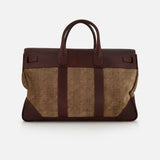 The BRUNELLO CUCINELLI Travel Duffle Bag with Chevron-effect features a combination of brown leather and tan herringbone fabric, two handles, a structured silhouette, and a distinctive vertical stripe pattern on the front. Reminiscent of vintage travel styles, this bag is shown against a white background and seamlessly blends timeless elegance with practical design.