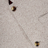 A close-up of the beige Water Resistant Cashmere Sport Jacket by BRUNELLO CUCINELLI showcases its textured, striped woven pattern with brown buttons and a visible pocket. The interior label reads BRUNELLO CUCINELLI, highlighting its Made in Italy craftsmanship.