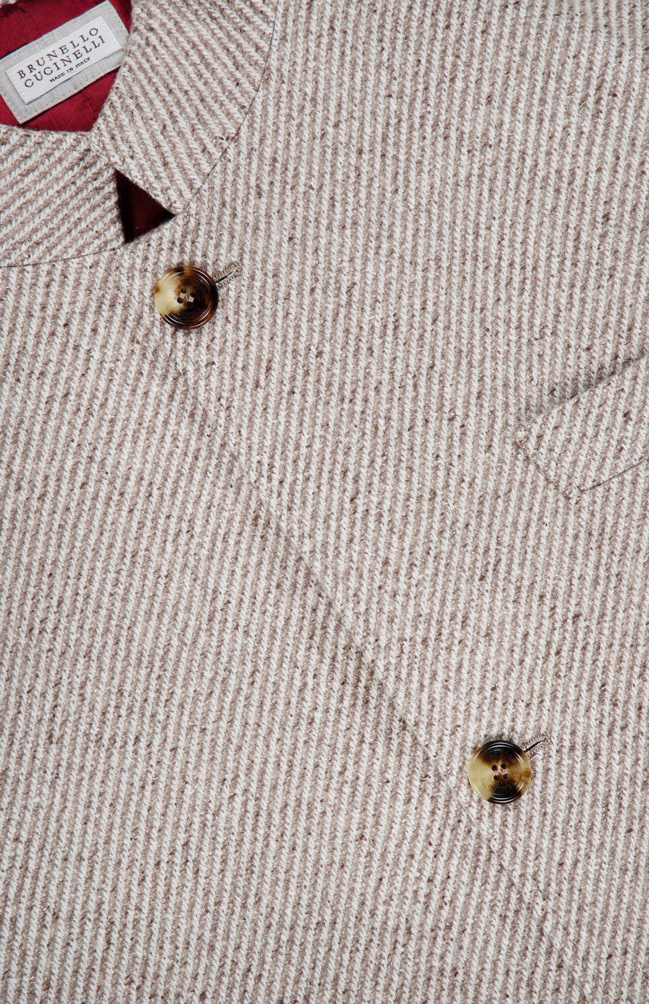 A close-up of the beige Water Resistant Cashmere Sport Jacket by BRUNELLO CUCINELLI showcases its textured, striped woven pattern with brown buttons and a visible pocket. The interior label reads BRUNELLO CUCINELLI, highlighting its Made in Italy craftsmanship.