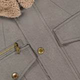 Close-up of the BRUNELLO CUCINELLI Water Resistant Safari Jacket in taupe, featuring gold buttons, a gold-zippered pocket, flap pockets, and a tan sherpa collar. The interior displays a white "Brunello Cucinelli Made in Italy" label.