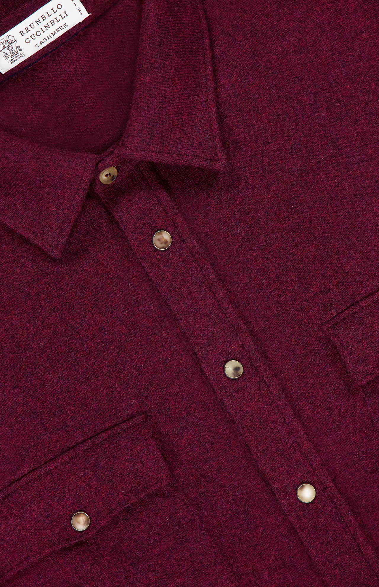 Close-up of a burgundy BRUNELLO CUCINELLI Snap-front Western Overshirt, crafted from a luxurious virgin wool, cashmere, and silk blend, featuring a snap-front closure, pointed collar, and two chest pockets with button flaps.