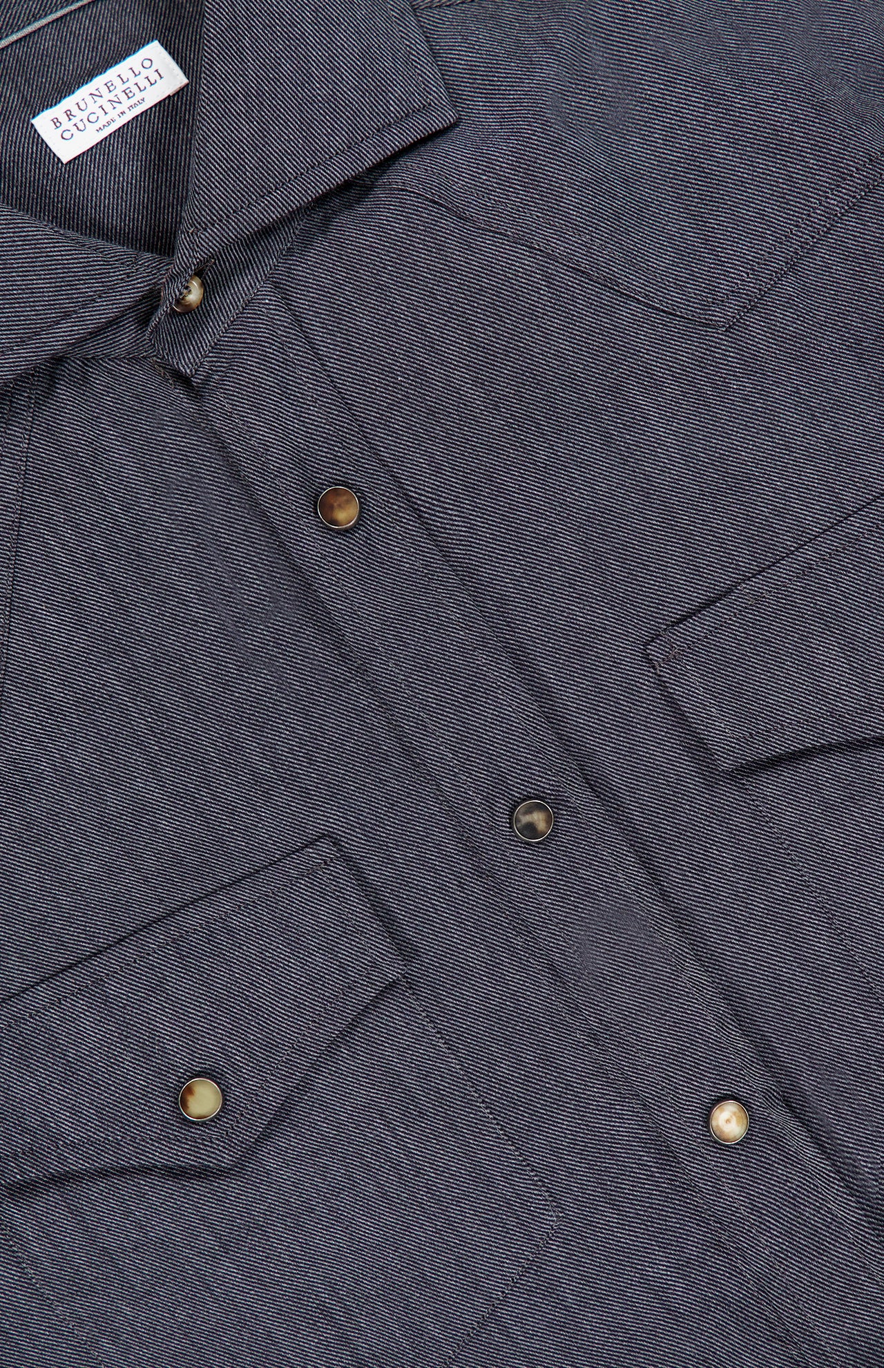 Close-up of the BRUNELLO CUCINELLI Western Snap-front Shirt in gray, featuring metal snap closures, two chest pockets with flaps, and a Buffalo Collection label visible inside the collar. The subtly textured fabric provides a refined look and feel reminiscent of cotton cashmere.