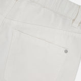 Close-up of the back of BRUNELLO CUCINELLI Piece-Dyed Cotton Pull-On Jeans, showing an elastic waistband, belt loops, and a single back pocket with a metal rivet at the corner.