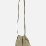 The BRUNELLO CUCINELLI Soft Suede Mini Pouchette Bag features light olive-green suede and leather, a long thin strap, and a gathered slouchy design, shown on a plain white background.
