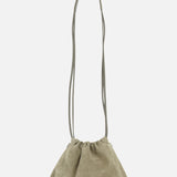 The Soft Suede Mini Pouchette Bag by BRUNELLO CUCINELLI features light olive green suede and leather, a long thin strap, and a soft, slouchy silhouette with minimalist design. Shown against a plain white background.