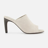 The BRUNELLO CUCINELLI Suede Curved Monili 80MM Mule Heel, in beige suede with a high tapered heel and minimalist slip-on design, is displayed in side view against a white background.