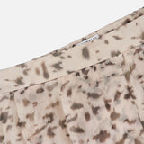 Close-up of the BRUNELLO CUCINELLI Artemis Animalier Print Silk Pleated Skirt, showcasing its light beige silk fabric adorned with a brown and gray abstract animal print pattern, delicate pleats, and a partially visible white tag at the waistband.