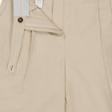 A pair of BRUNELLO CUCINELLI Cotton Linen Bull Bermuda Pleated Shorts in beige, partially unzipped and unbuttoned to reveal the inner waistband, fly with buttons, zipper, and interior lining detail.