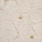 Close-up of the Fuzzy Cotton Bull Cropped Jacket by BRUNELLO CUCINELLI, featuring off-white textured fabric with a curly, fringed surface and shiny gold buttons for striking contrast.