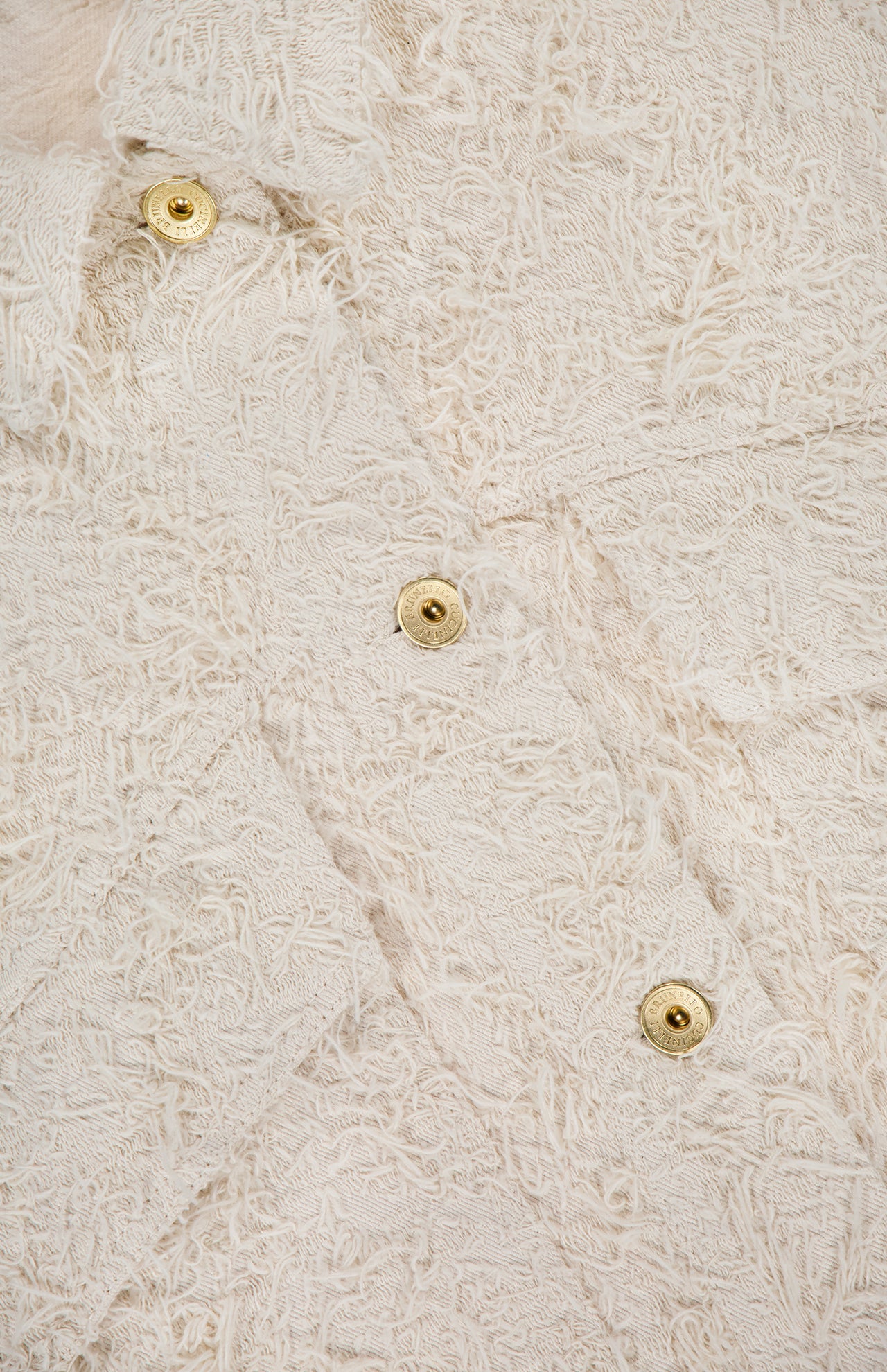 Close-up of the Fuzzy Cotton Bull Cropped Jacket by BRUNELLO CUCINELLI, featuring off-white textured fabric with a curly, fringed surface and shiny gold buttons for striking contrast.