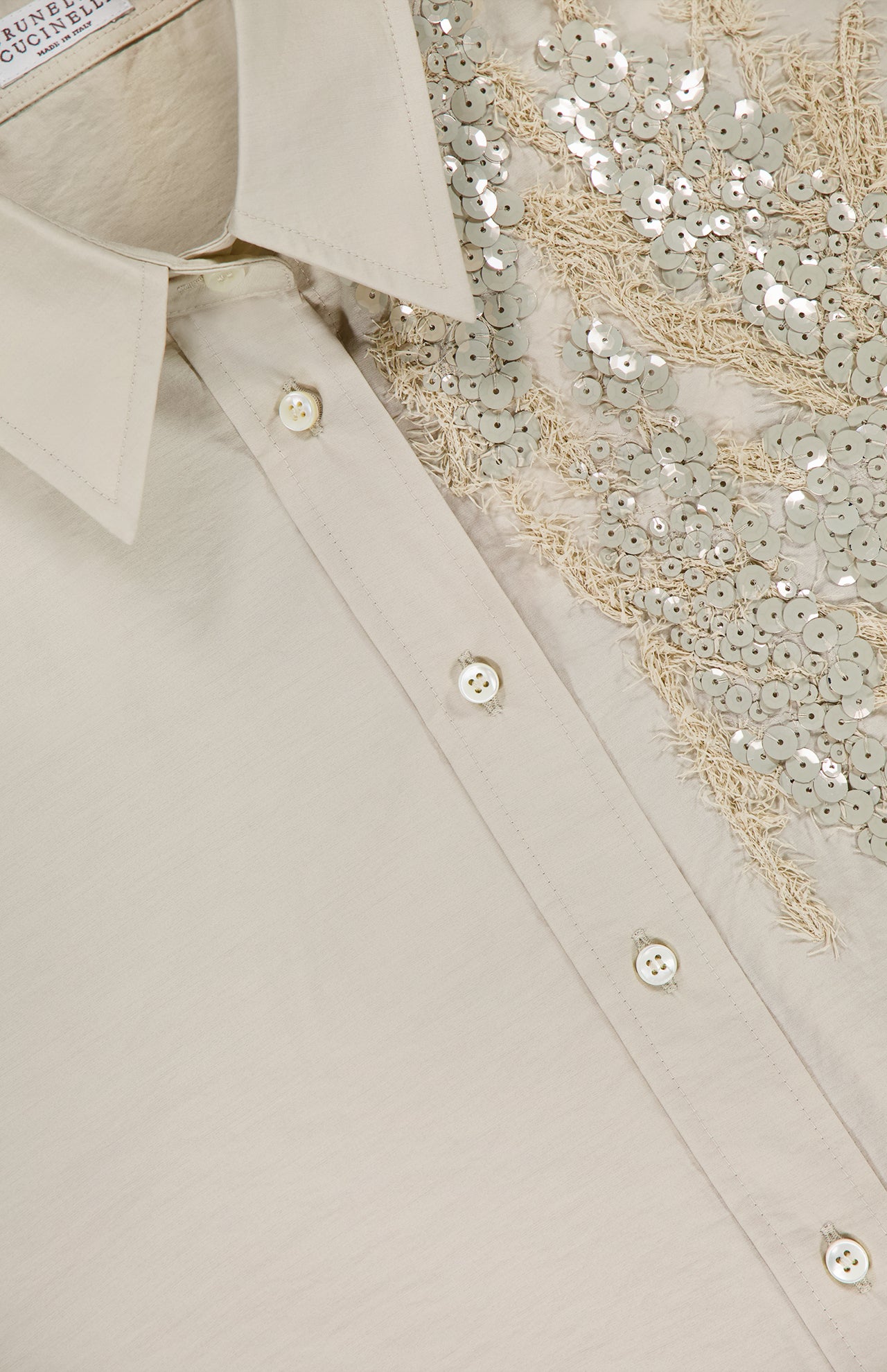 Close-up of the Halo Effect Embroidery Cotton Poplin Shirt by BRUNELLO CUCINELLI, featuring plain quartz-colored fabric, decorative sequins with seabed embroidery, a classic collar, and white buttons.