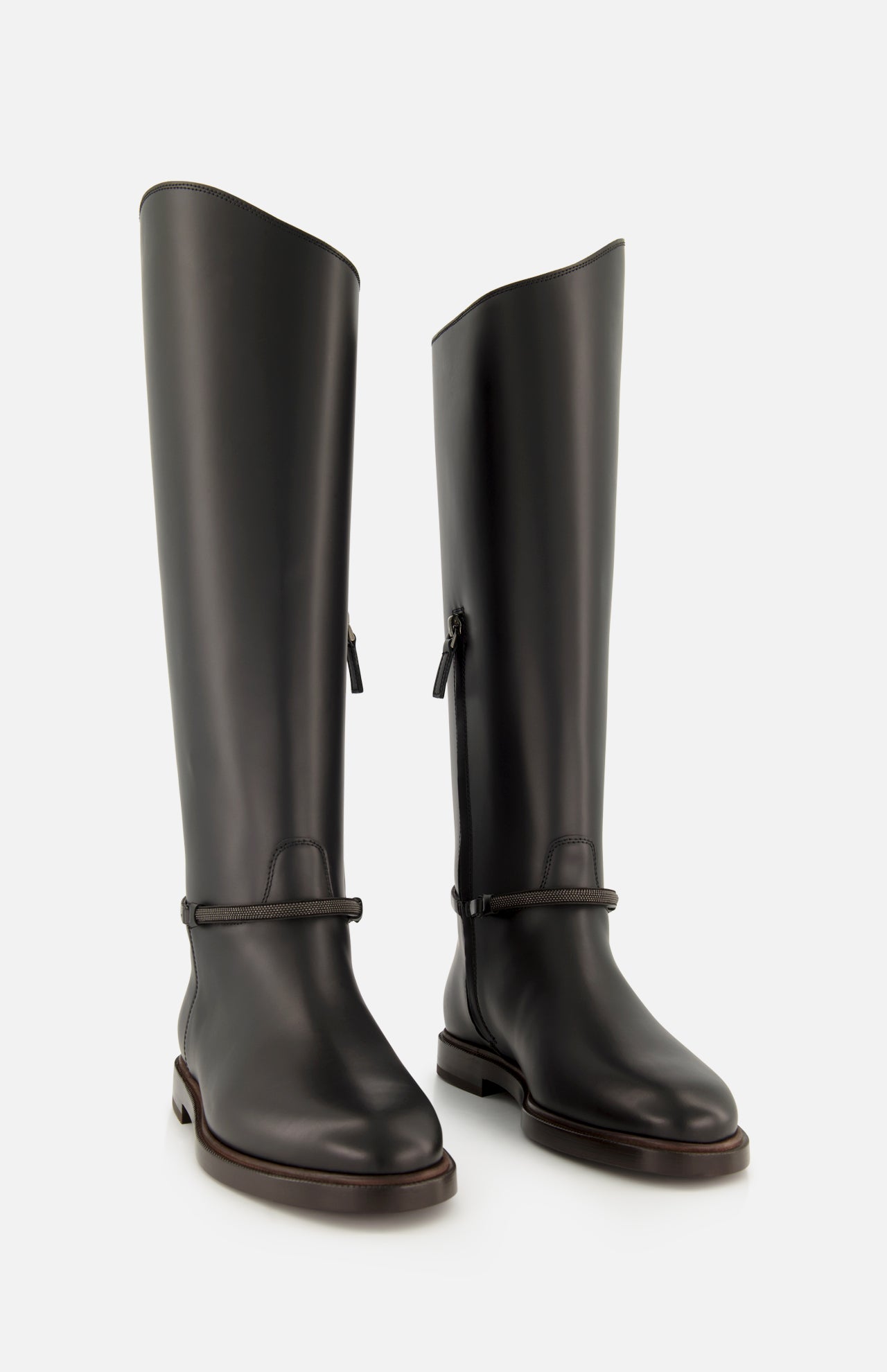 A pair of BRUNELLO CUCINELLI Leather Monili Band Tall Riding Boots in sleek black leather feature a rounded toe and subtle strap detailing at the ankle, set against a plain white background—ideal for those seeking classic knee-high equestrian boots with timeless sophistication.