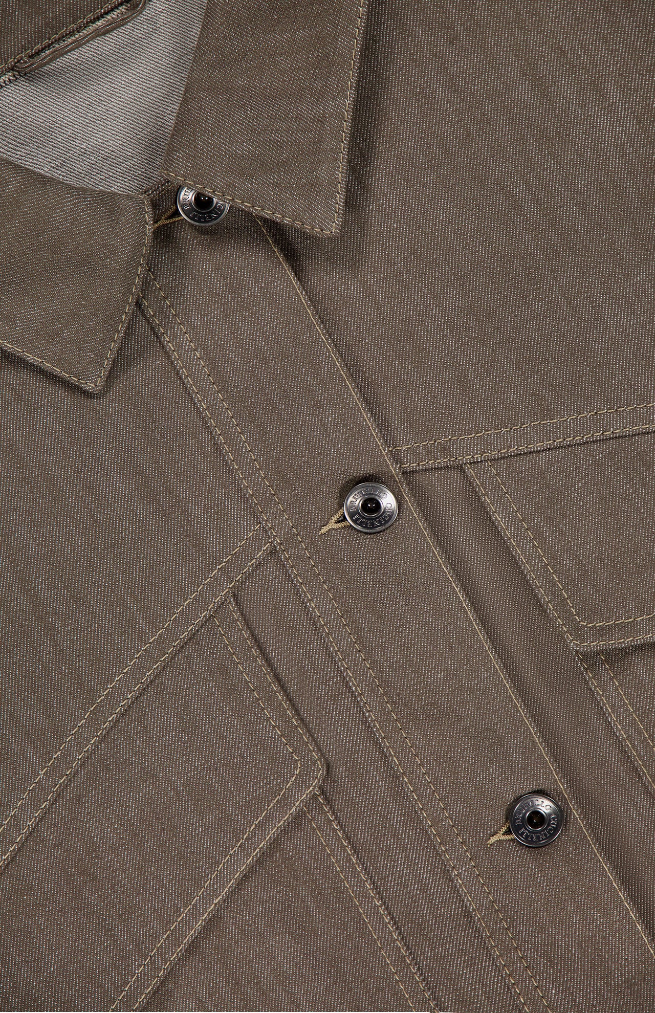 Close-up of the No Fade Indigo Cropped Jacket by BRUNELLO CUCINELLI, featuring part of the collar, three dark buttons, visible seams, two angled chest pockets, and detailed stitching on indigo denim fabric.
