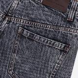 Close-up of the Prince Of Whales Embossed Wide Barrel Jean by BRUNELLO CUCINELLI, showcasing its dark blue barrel fit silhouette, a back pocket with brown stitching details, and a brown leather BRUNELLO CUCINELLI brand patch on the waistband.