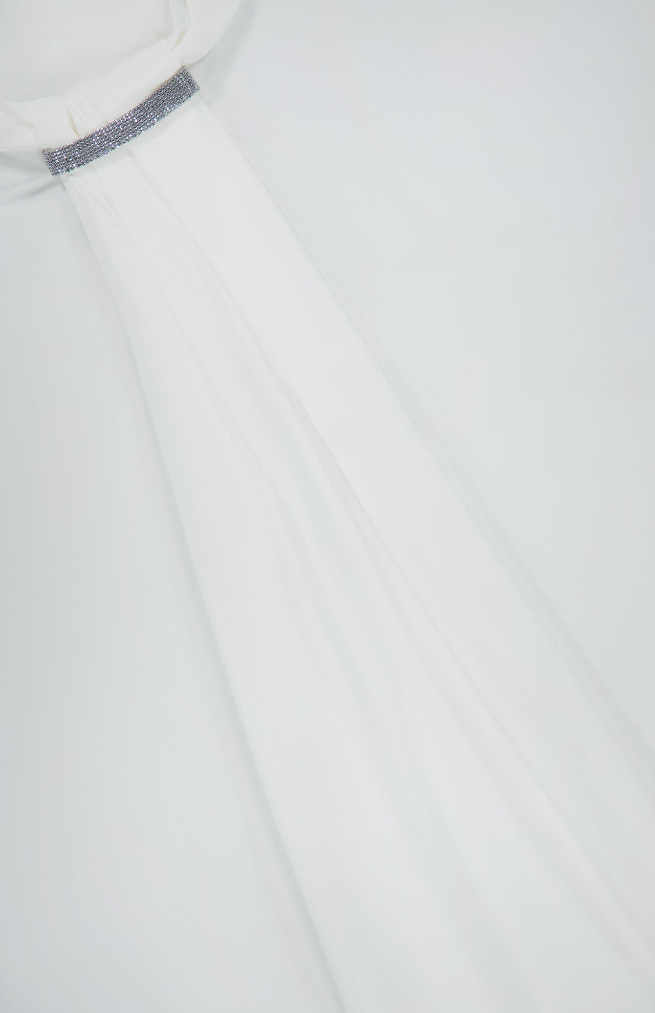 A close-up of the BRUNELLO CUCINELLI Silk Long Sleeve Blouse showcases flowing white silk fabric with a high gathered neckline, accented by a sparkling, beaded band evocative of monili embroidery. The luxurious material drapes elegantly across a plain background, highlighting the refined silhouette of this blouse.