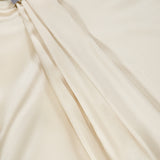 Close-up of a smooth, cream-colored silk satin fabric with gentle folds and a rhinestone-embellished buckle detail near the top left corner, evocative of the luxurious finish on the BRUNELLO CUCINELLI Silk Satin Tie Sleeveless Blouse.