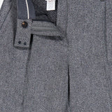 Close-up of the BRUNELLO CUCINELLI Sparkling Herringbone Loose Pleated Pant in silver-grey, featuring a classic herringbone pattern. The front button, zipper, and waistband are partially open to showcase the interior lining and brand label. Expertly crafted in Italy from fine wool.