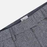 Close-up of the Sparkling Herringbone Loose Pleated Pant in silver-grey wool with prominent pleats and a visible BRUNELLO CUCINELLI label on the inner waistband, showcasing refined craftsmanship and classic Italian style.