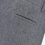 Close-up of the Sparkling Herringbone Loose Pleated Pant by BRUNELLO CUCINELLI, highlighting the fine gray herringbone texture and meticulous Italian craftsmanship. The image showcases the detailed fabric pattern and precise tailoring.