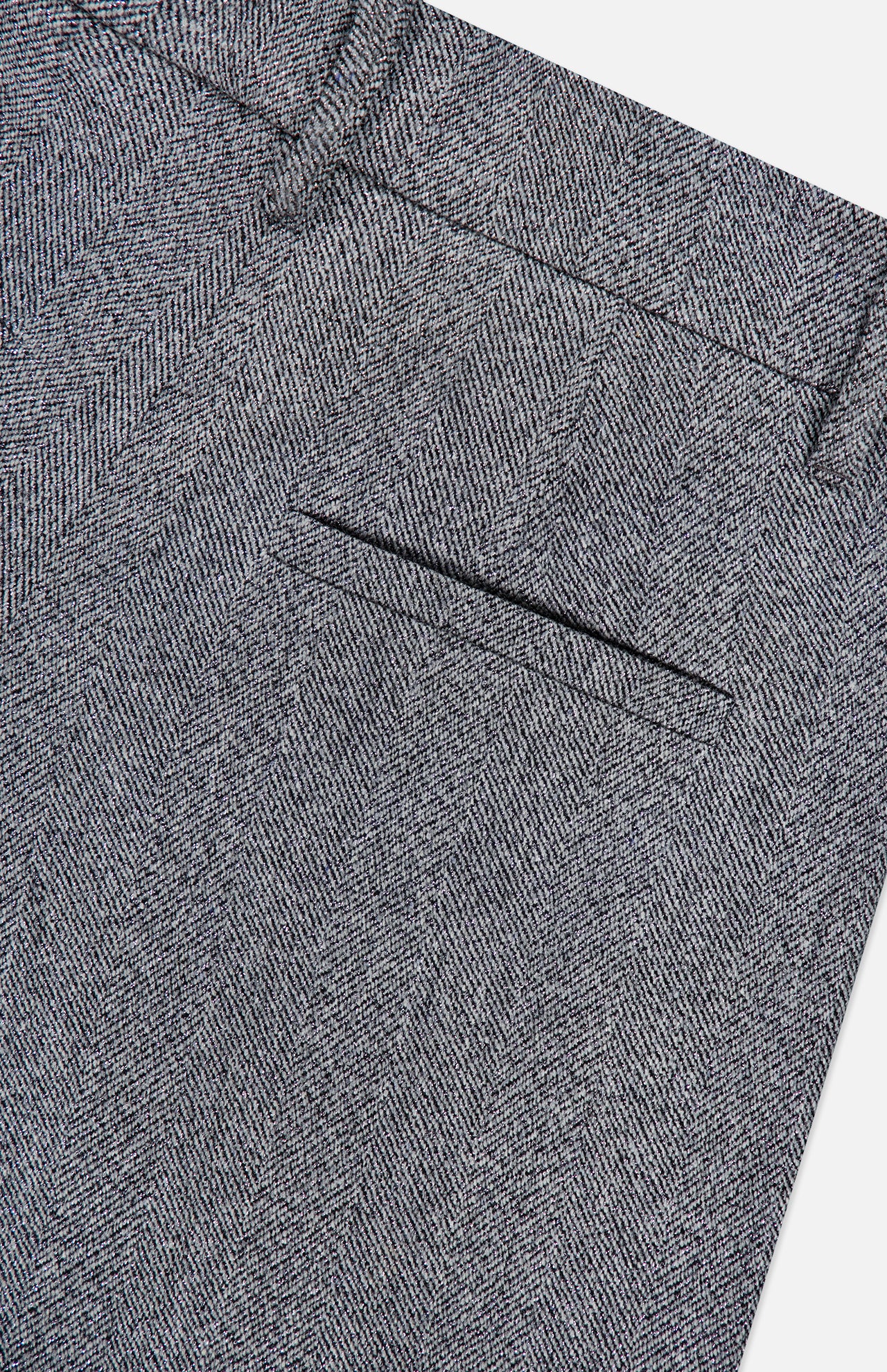 Close-up of the Sparkling Herringbone Loose Pleated Pant by BRUNELLO CUCINELLI, highlighting the fine gray herringbone texture and meticulous Italian craftsmanship. The image showcases the detailed fabric pattern and precise tailoring.