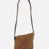 The Suede Mini Pouchette with Monili by BRUNELLO CUCINELLI stands upright against a plain white background. Crafted in a warm caramel-toned brown suede, the bag features a simple rectangular silhouette with visible front stitching and is finished with a long, dark strap—capturing Brunello Cucinelli’s signature sense of refinement.