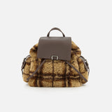 The BRUNELLO CUCINELLI Tartan Curly Shearling Backpack showcases a stylish design with a brown leather flap and handle, complemented by soft, curly yellow and brown plaid shearling in a classic tartan pattern on the main body and sides, all presented against a plain white background.