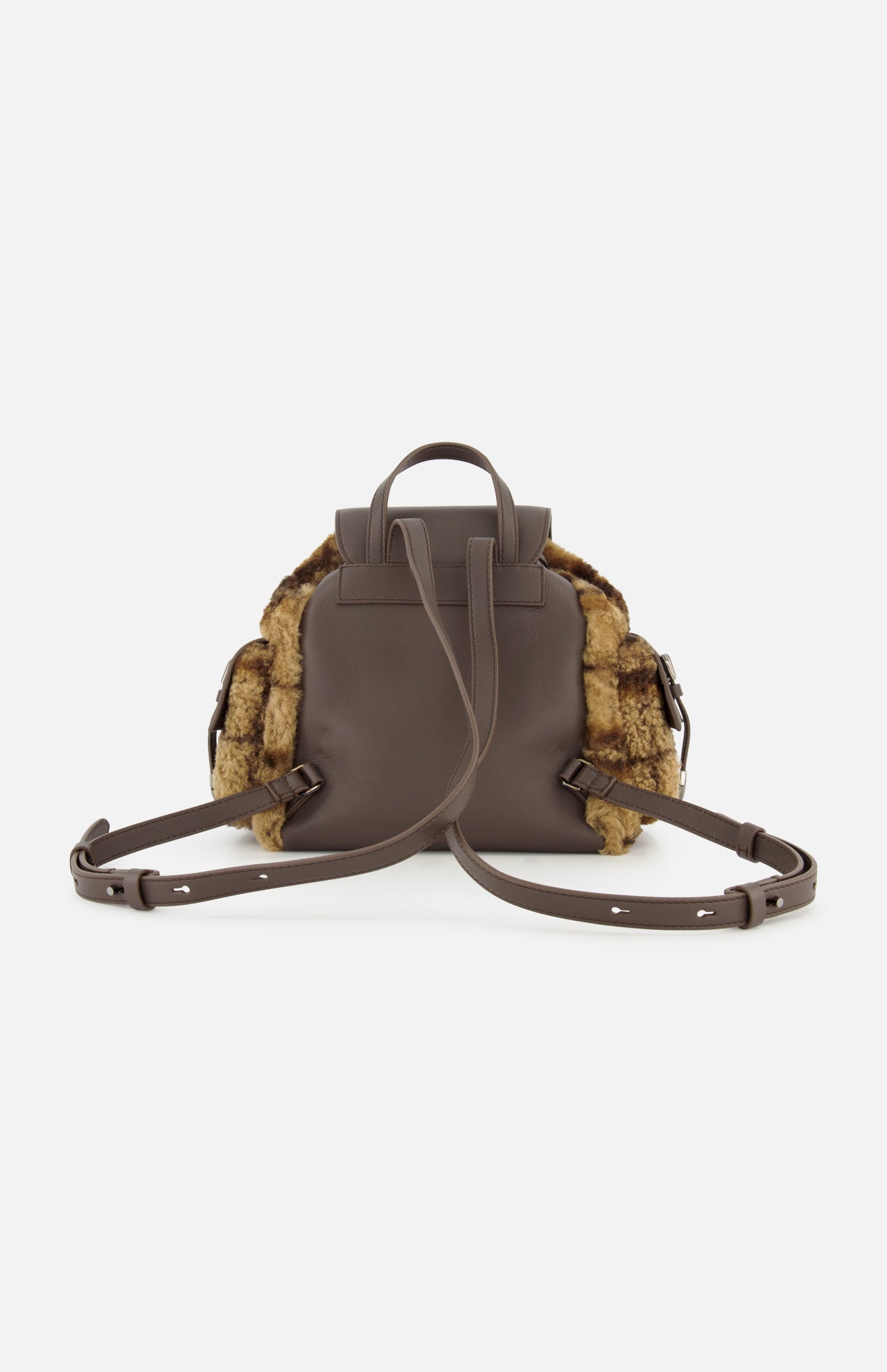 The BRUNELLO CUCINELLI Tartan Curly Shearling Backpack features brown leather construction, adjustable straps, a top handle, and plush brown fur accents on the sides. Photographed from the back against a white background, this stylish bag combines practicality with cozy shearling texture.