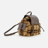 The BRUNELLO CUCINELLI Tartan Curly Shearling Backpack is a small leather backpack showcasing a brown and tan tartan curly shearling body, complemented by a brown leather flap, front pocket, and adjustable straps, displayed against a plain white background.