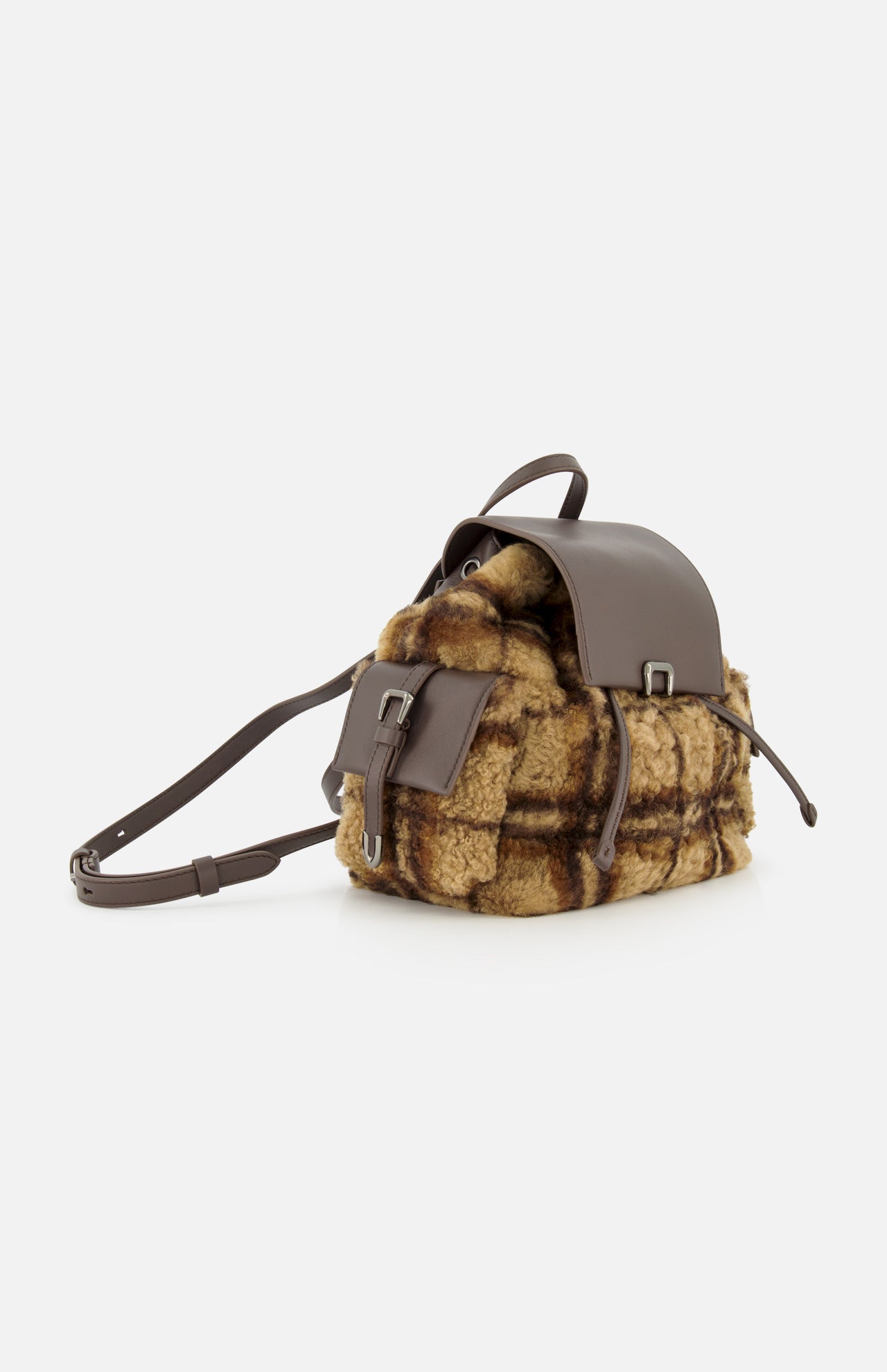 The BRUNELLO CUCINELLI Tartan Curly Shearling Backpack is a small leather backpack showcasing a brown and tan tartan curly shearling body, complemented by a brown leather flap, front pocket, and adjustable straps, displayed against a plain white background.